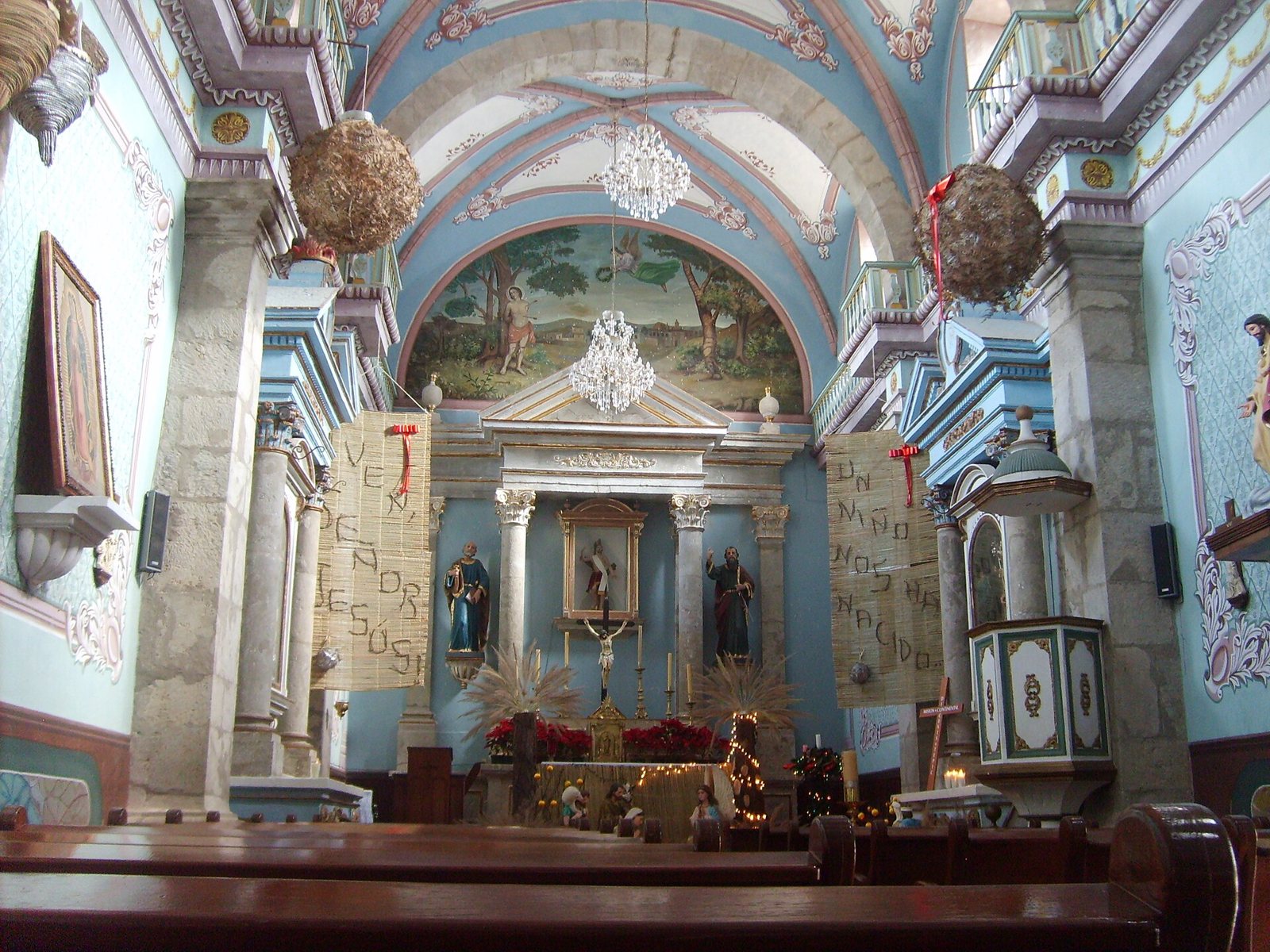 Interior of the San Sebastián parish church with a painted vaulted ceiling, chandeliers and main altar