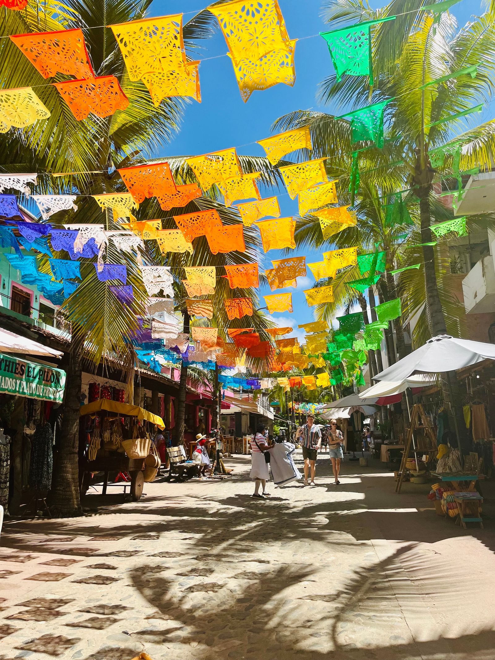 Pedestrian street in Sayulita decorated with colorful papel picado and palm trees