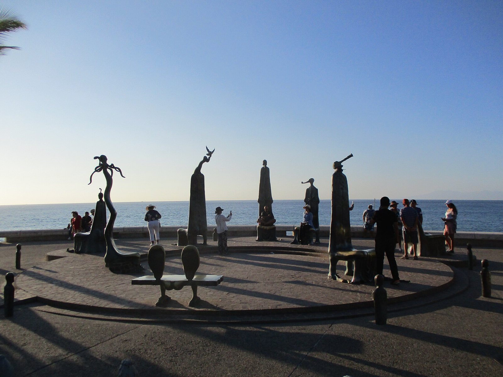 Bronze chairs and figures of the Rotunda by the Sea on the Malecón, with the ocean behind