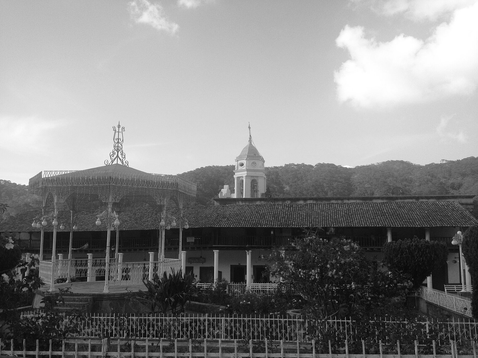 Black-and-white photo of the San Sebastián del Oeste main square with its bandstand, arcades and church tower