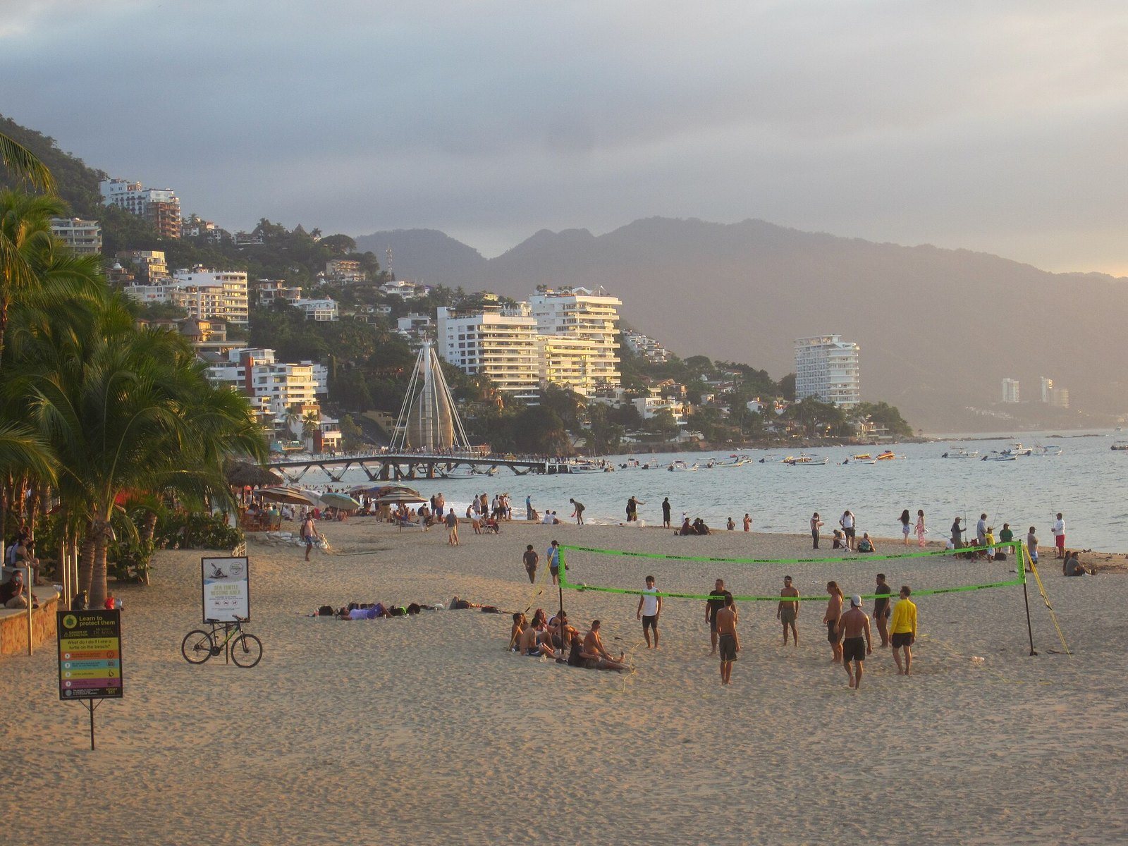 Los Muertos Beach at dusk with people playing volleyball and the pier behind