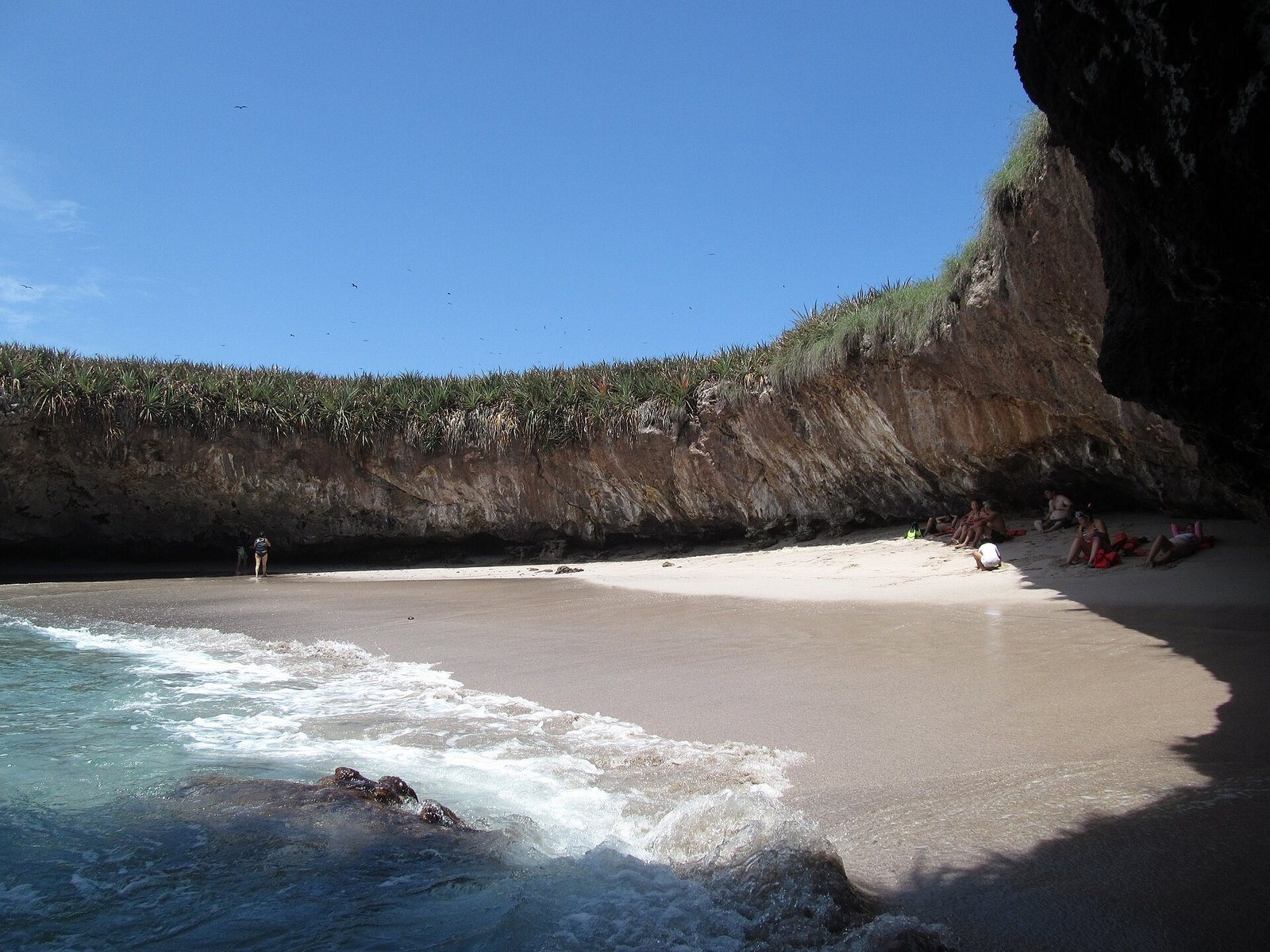 Hidden Beach seen from the water, ringed by rock walls topped with vegetation
