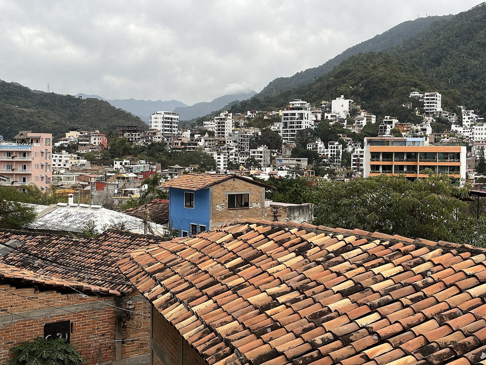 Terracotta tile roofs and hillside homes in downtown Puerto Vallarta with the Sierra Madre behind