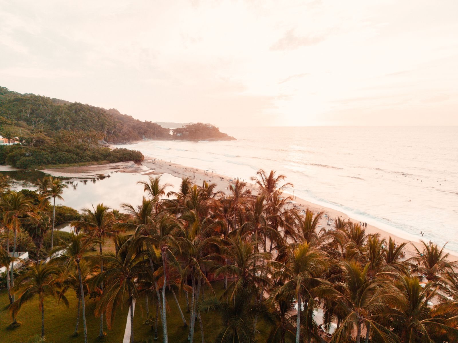 Aerial view of the beach in San Francisco, Nayarit, at sunset, with palm trees, a lagoon and a green headland
