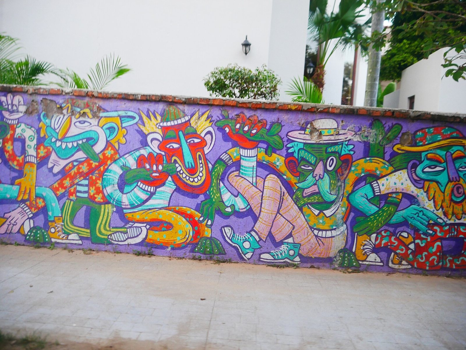 Colorful mural on a purple wall with cartoon-style characters in hats, near the beach entrance in San Pancho
