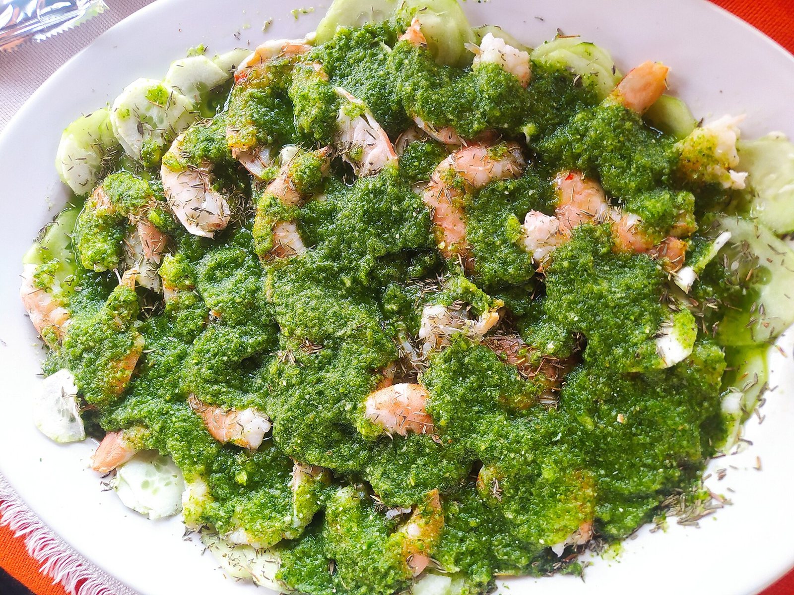 Plate of green aguachile with shrimp covered in green chile sauce over cucumber slices