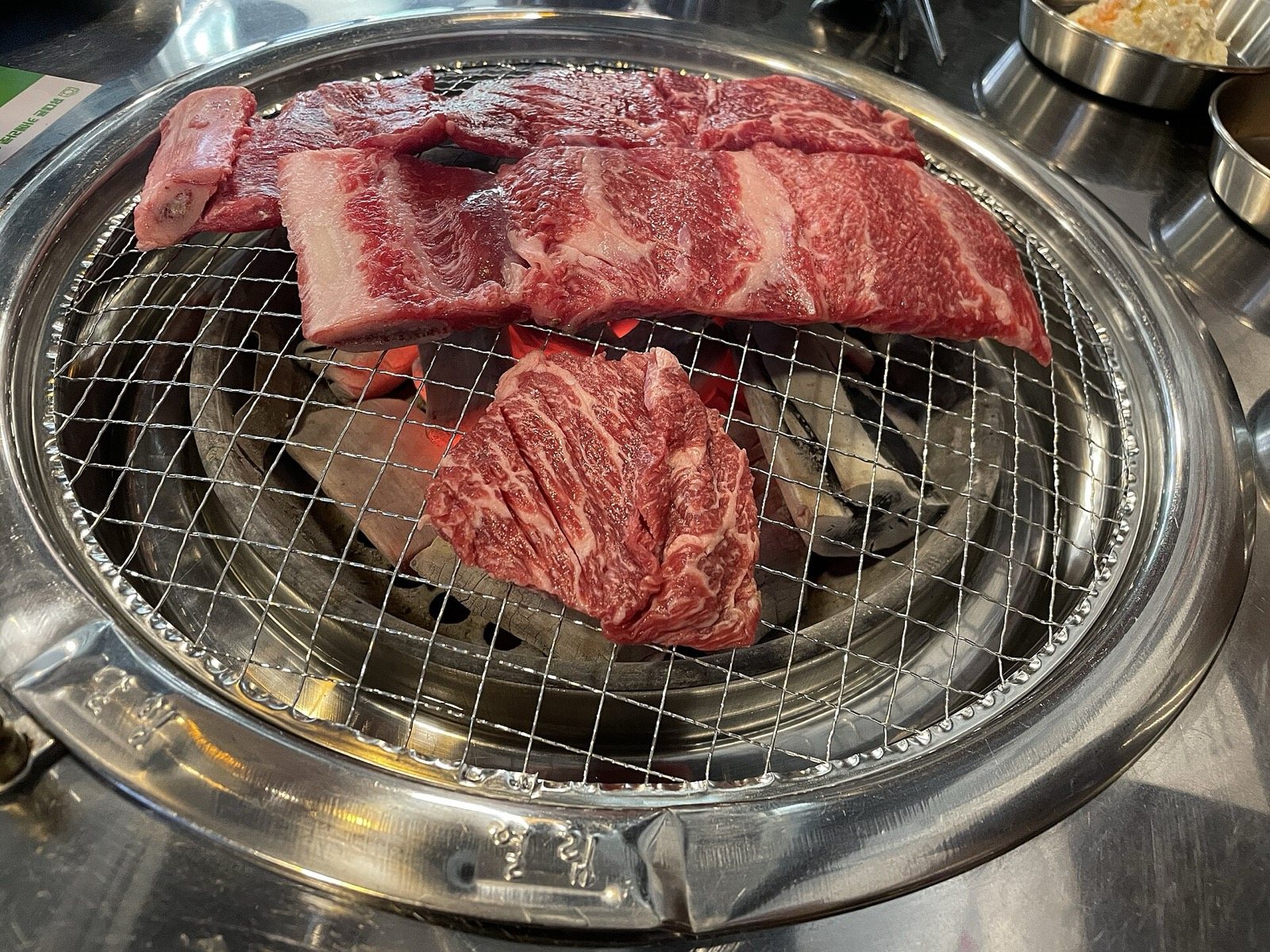 Marbled beef cuts cooking on a charcoal tabletop grill, Korean style