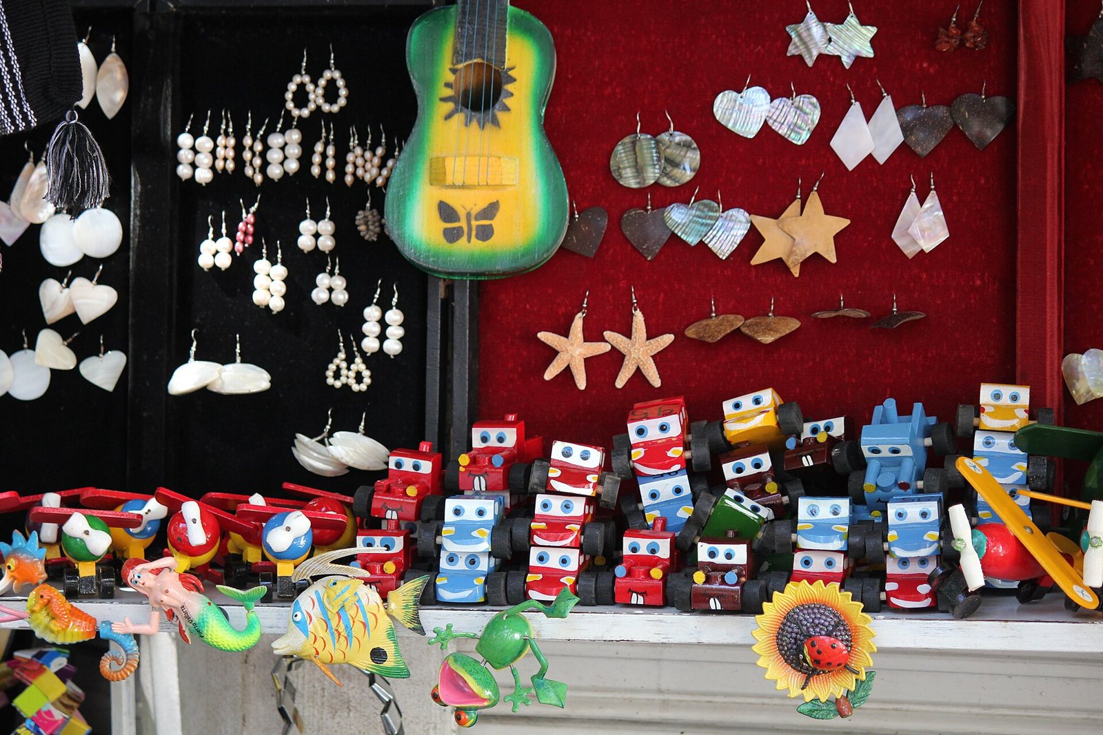 Souvenir stall with shell and mother-of-pearl earrings, a painted toy guitar, colorful wooden toy cars and sea-creature magnets